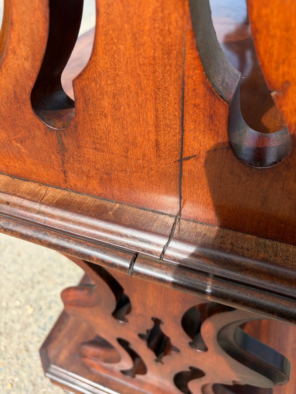 A Victorian mahogany three-tier buffet featuring carved pierced side supports, open rectangular shelves, and turned feet resting on original castors. View X