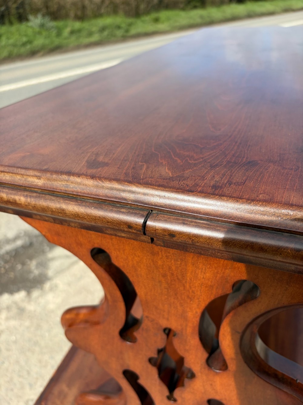 A Victorian mahogany three-tier buffet featuring carved pierced side supports, open rectangular shelves, and turned feet resting on original castors. View XI