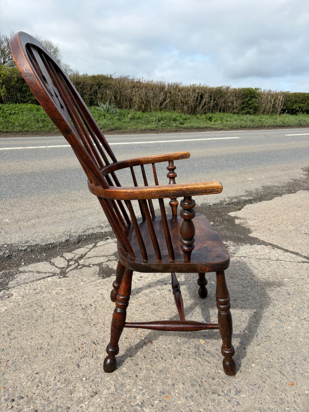 A 19th-century dark elm and beech Windsor armchair featuring a pierced central splat, hoop back, turned spindles, and turned legs. View III