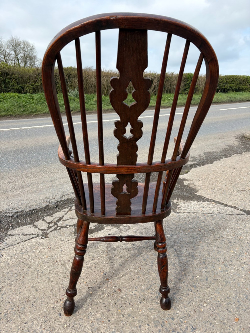 A 19th-century dark elm and beech Windsor armchair featuring a pierced central splat, hoop back, turned spindles, and turned legs. View IV