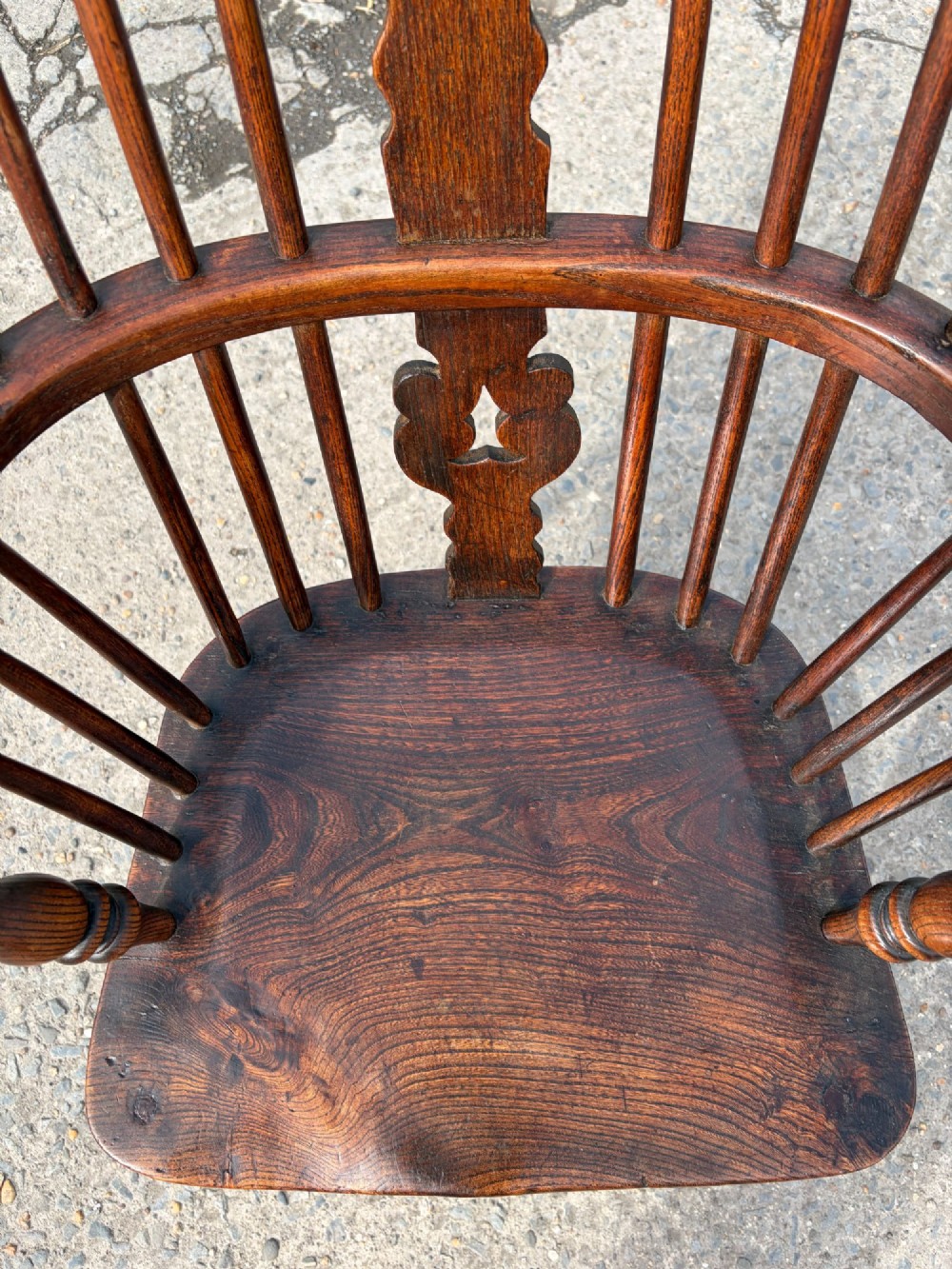 A 19th-century dark elm and beech Windsor armchair featuring a pierced central splat, hoop back, turned spindles, and turned legs. View V