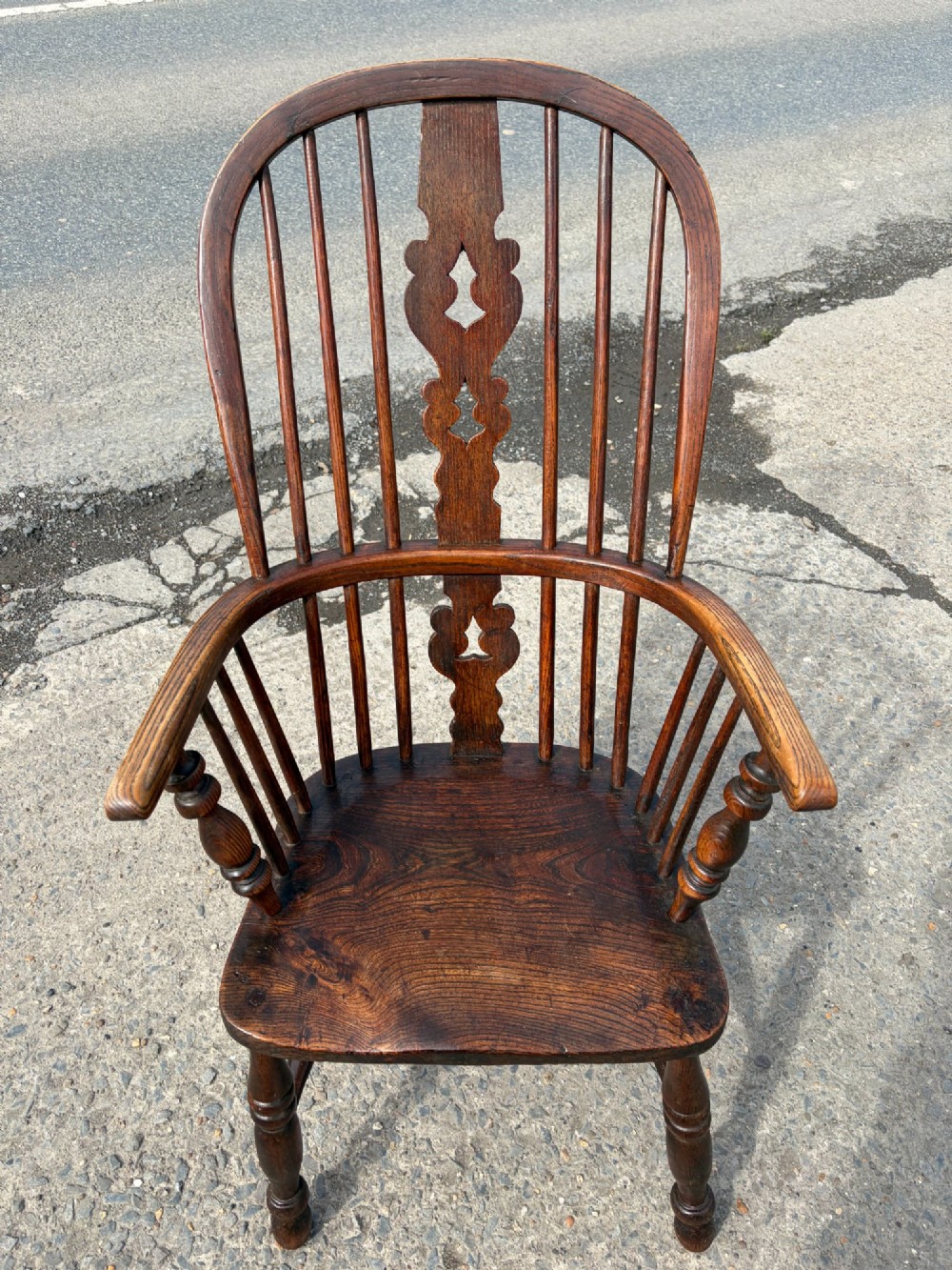 A 19th-century dark elm and beech Windsor armchair featuring a pierced central splat, hoop back, turned spindles, and turned legs. View VI