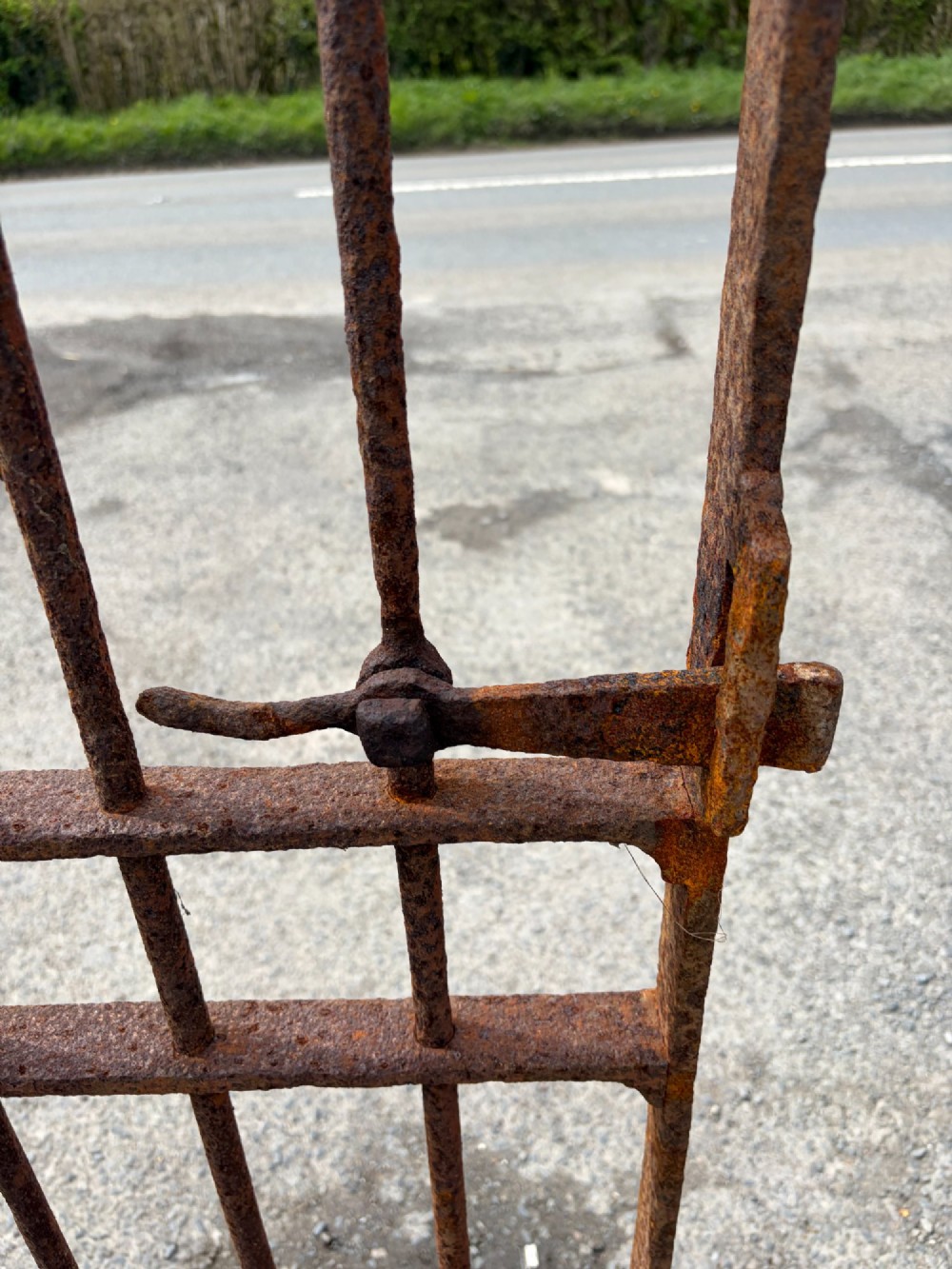 A tall late 19th-century wrought iron gate featuring an arched top rail, vertical bars, riveted joinery, and a rusted surface patina. View II