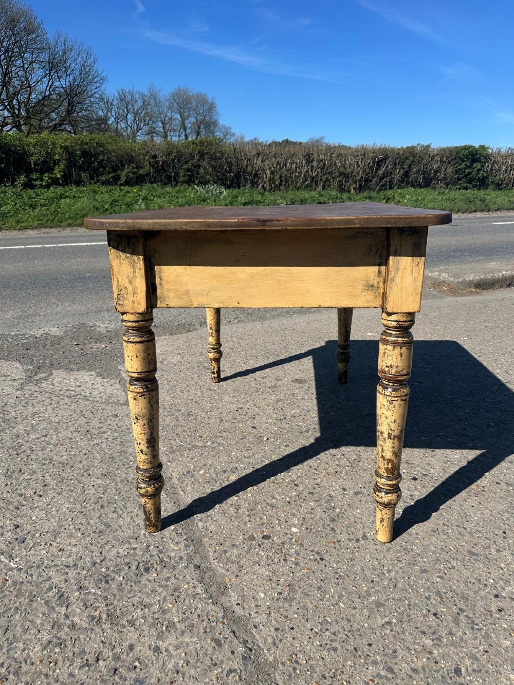 A Victorian pine table featuring a natural wood top, a single drawer with a round wooden knob, and turned yellow painted legs showing light surface wear. View III