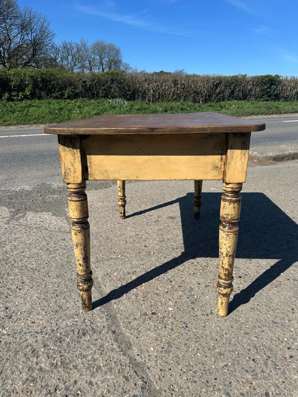 A Victorian pine table featuring a natural wood top, a single drawer with a round wooden knob, and turned yellow painted legs showing light surface wear. View IV