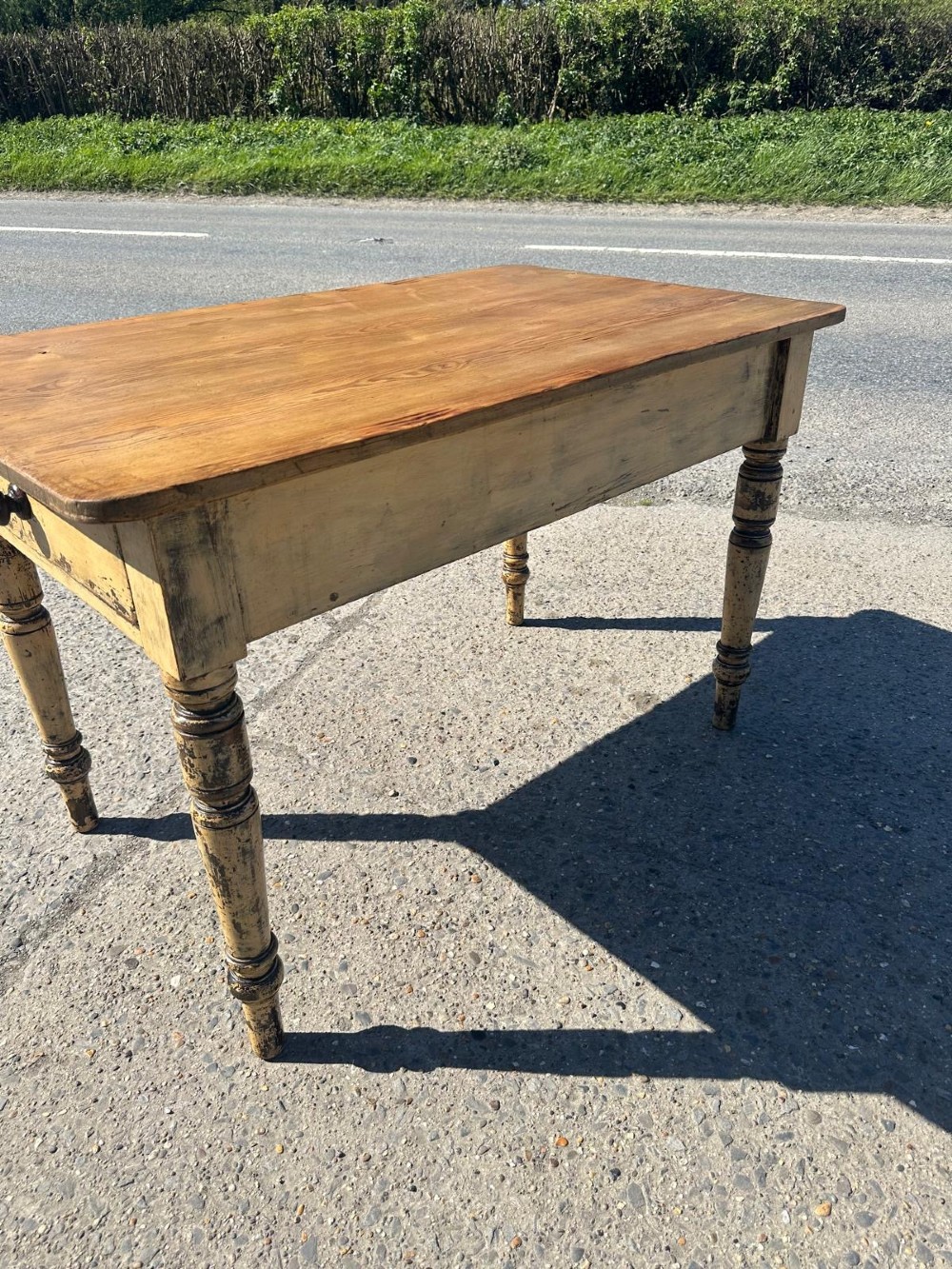 A Victorian pine table featuring a natural wood top, a single drawer with a round wooden knob, and turned yellow painted legs showing light surface wear. View V