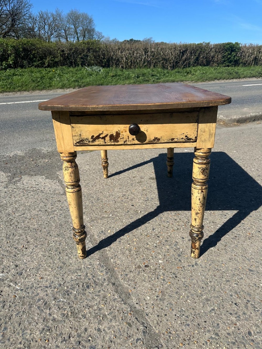 A Victorian pine table featuring a natural wood top, a single drawer with a round wooden knob, and turned yellow painted legs showing light surface wear. View XI