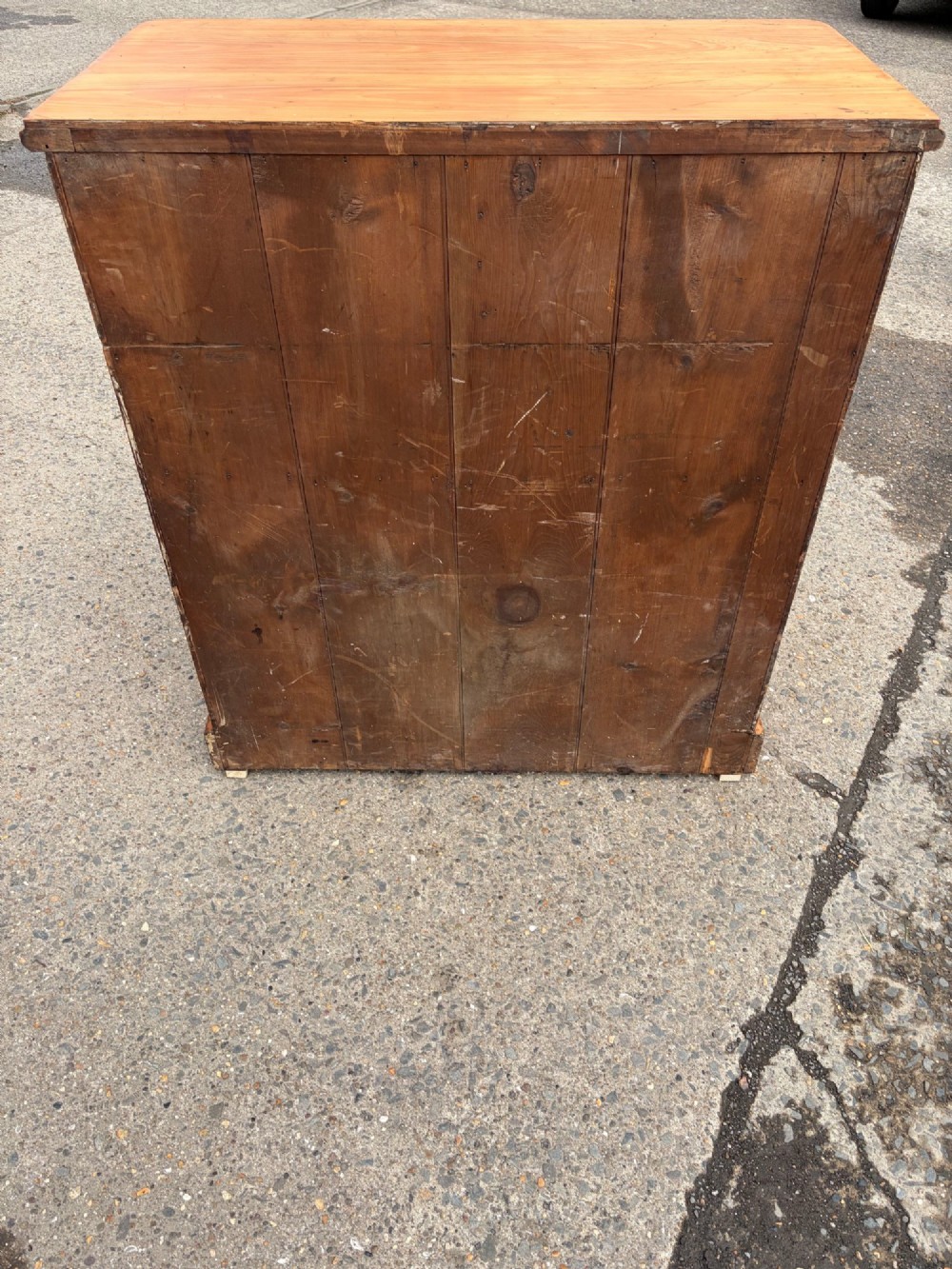 A Victorian pine chest of drawers featuring two short over three long graduated drawers with brass handles and carved edge trim. View V