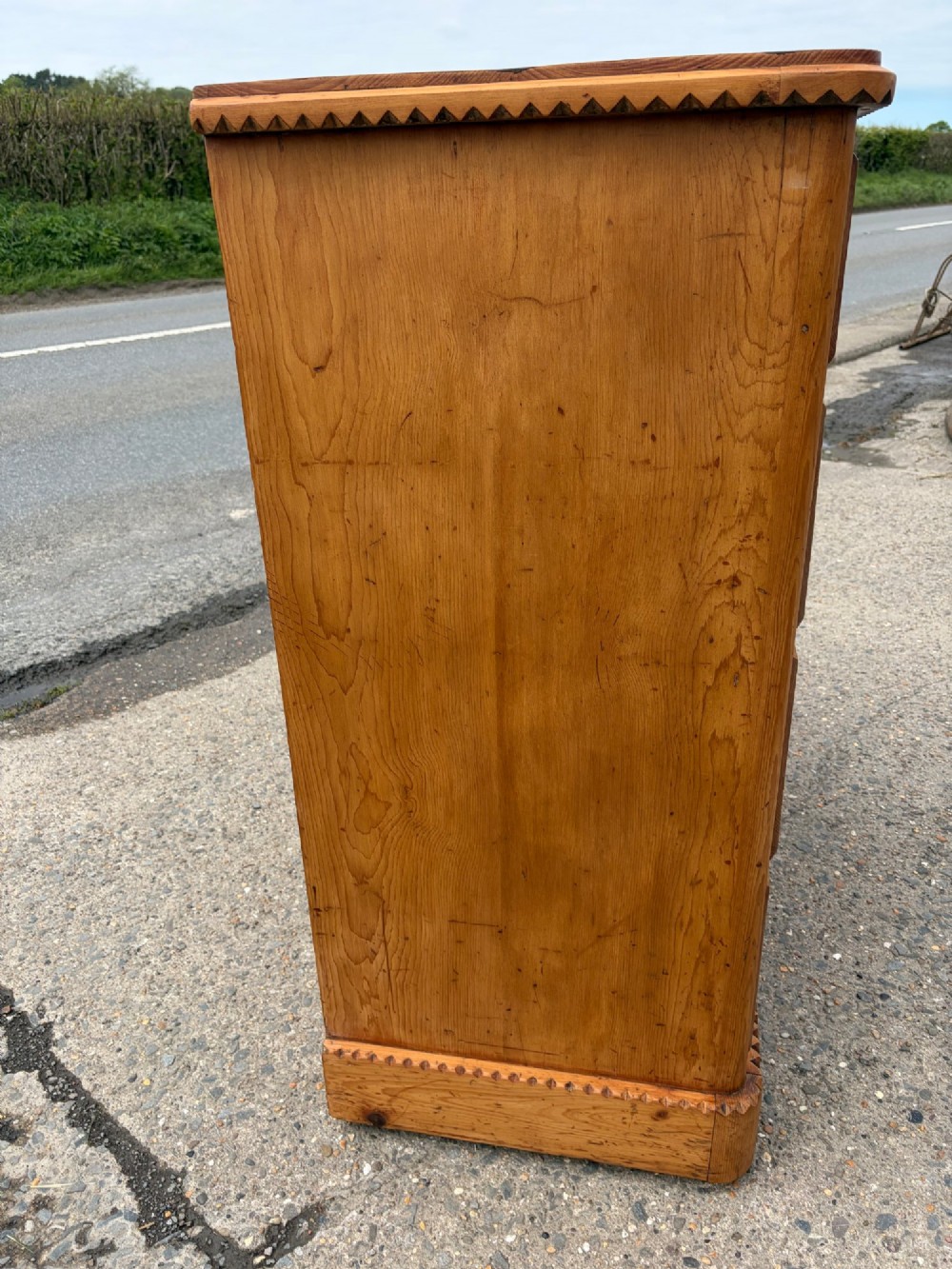 A Victorian pine chest of drawers featuring two short over three long graduated drawers with brass handles and carved edge trim. View VII