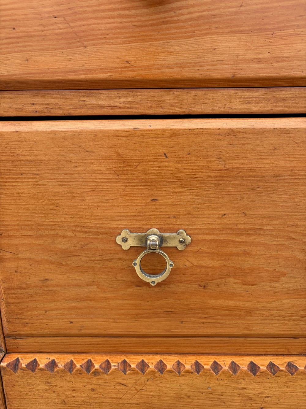 A Victorian pine chest of drawers featuring two short over three long graduated drawers with brass handles and carved edge trim. View XI