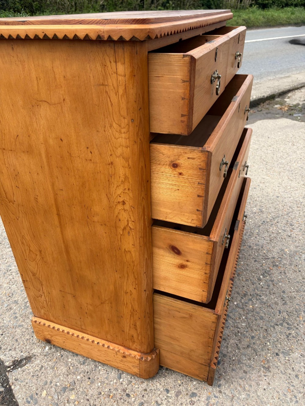 A Victorian pine chest of drawers featuring two short over three long graduated drawers with brass handles and carved edge trim. View XIII