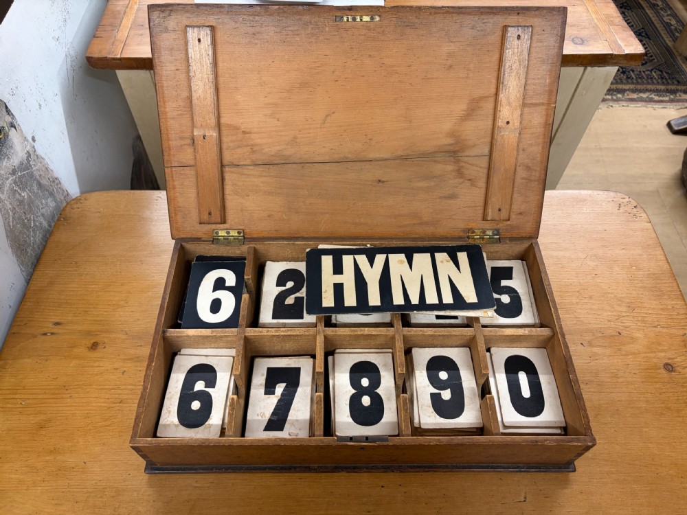 An antique Edwardian dark wood church hymn board with slotted rails holding printed cards for Hymn, Tune, and number digits. View IV