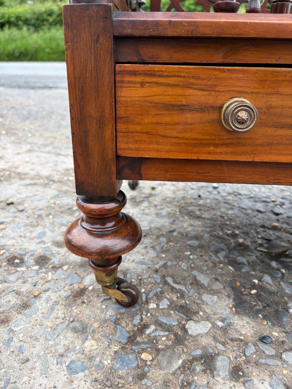A Victorian walnut canterbury with pierced fretwork dividers, turned corner posts, finials, a lower drawer, and brass castors. View VII