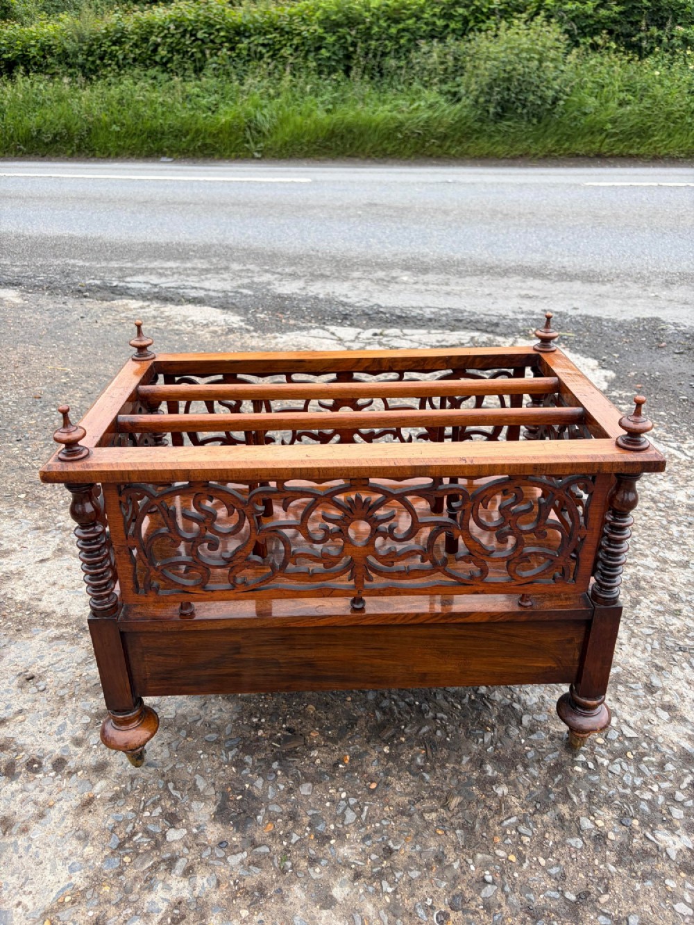 A Victorian walnut canterbury with pierced fretwork dividers, turned corner posts, finials, a lower drawer, and brass castors. View VIII