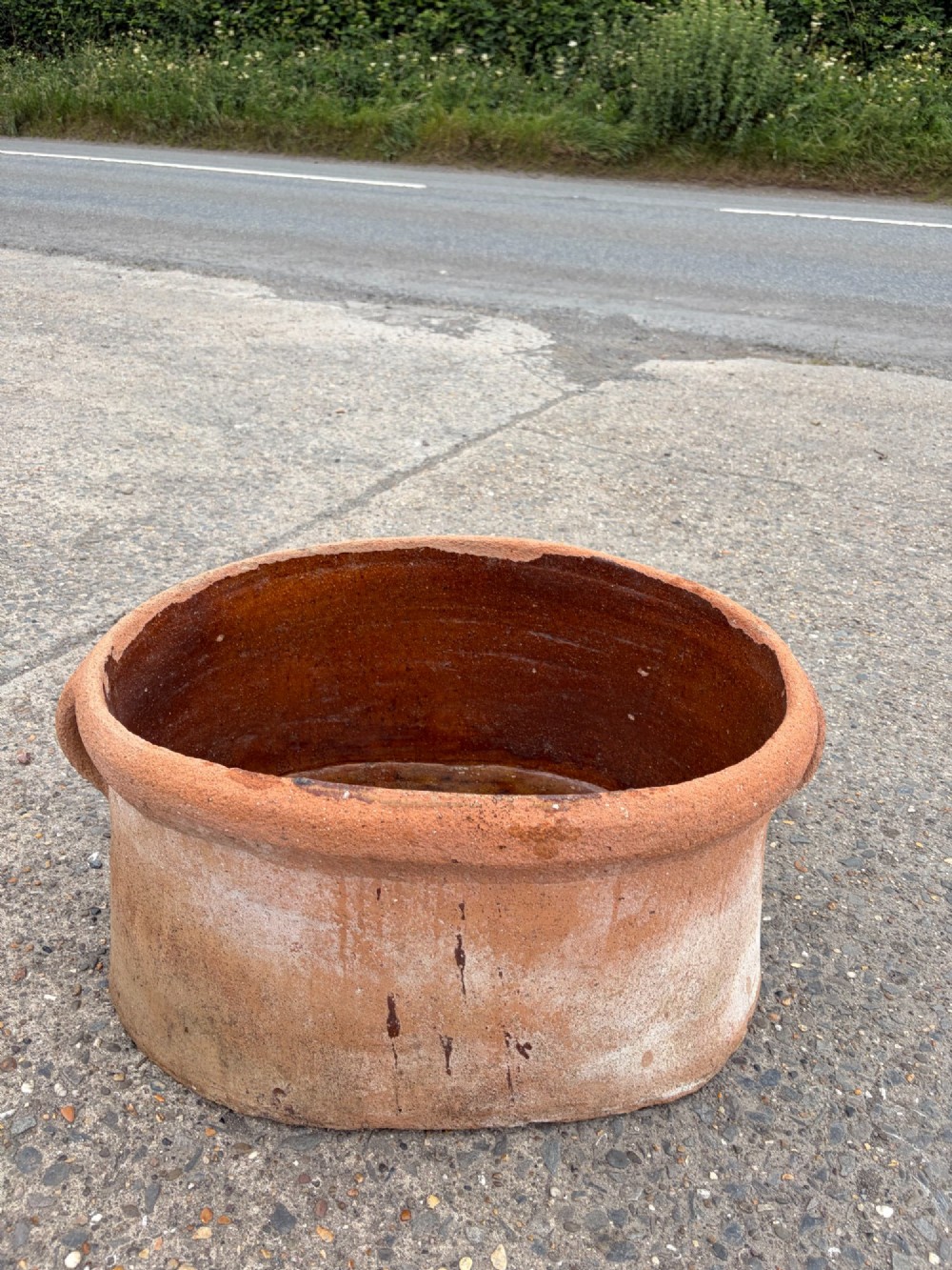 A large 19th-century oval terracotta salting trough with a weathered unglazed exterior and an amber lead-glazed interior. View V