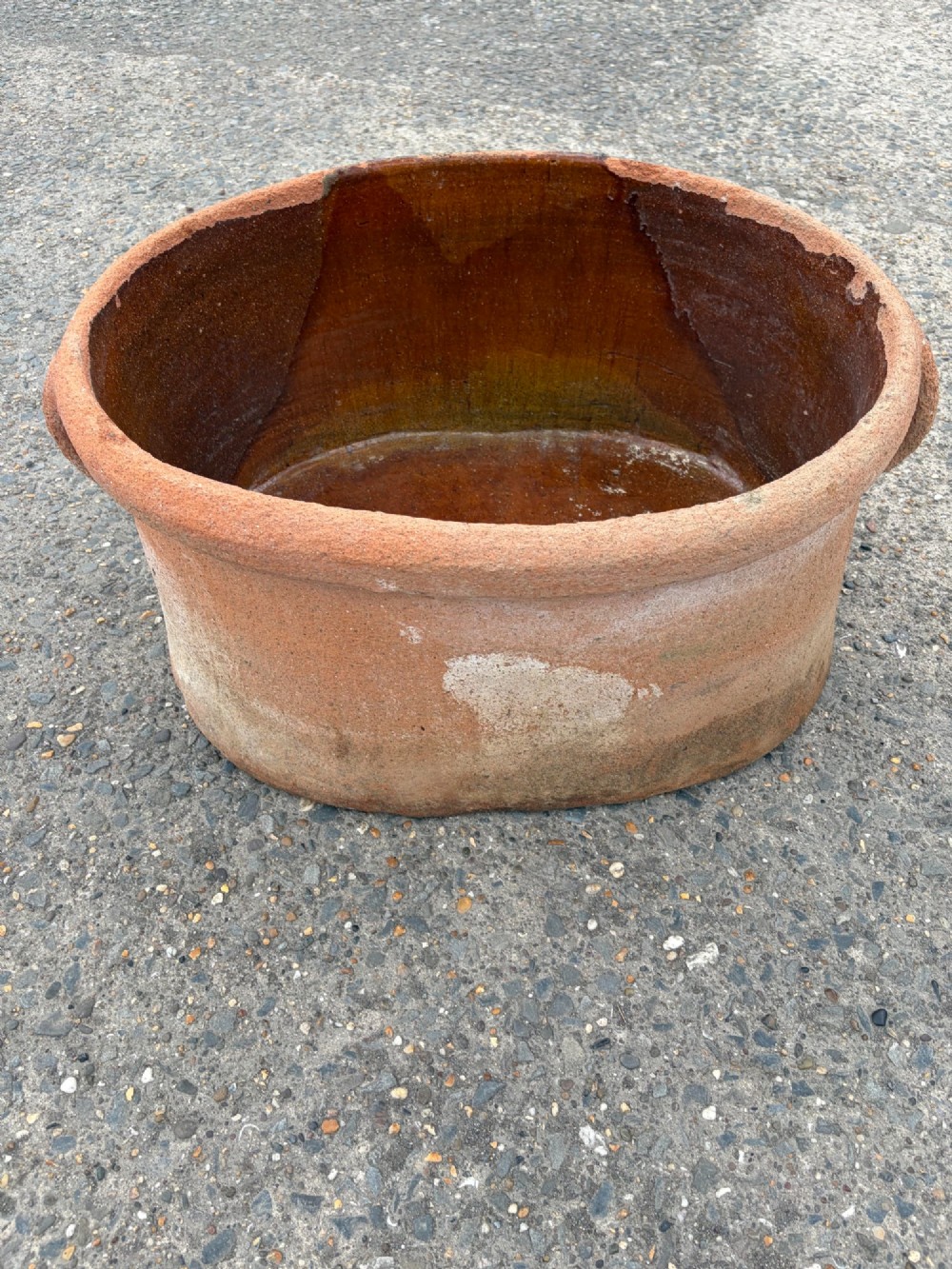 A large 19th-century oval terracotta salting trough with a weathered unglazed exterior and an amber lead-glazed interior. View VII