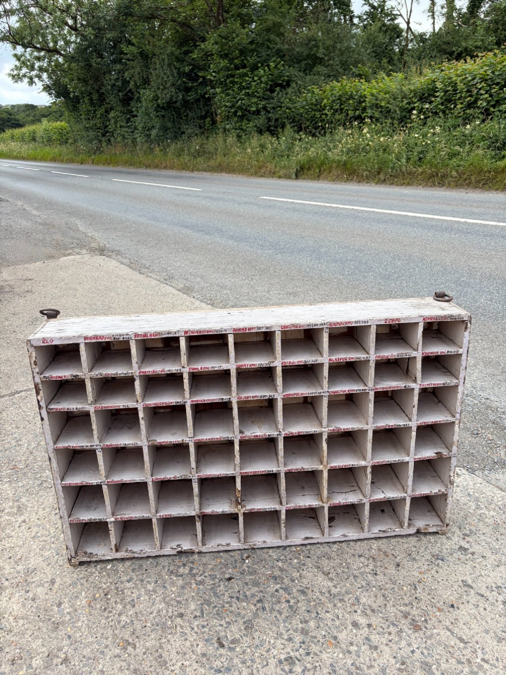 An early twentieth-century painted pine pigeon hole storage unit with a rectangular grid layout and red painted slot labels. View II