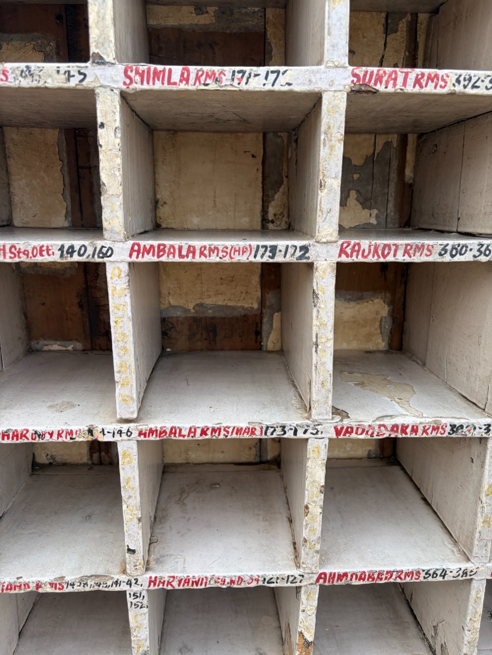 An early twentieth-century painted pine pigeon hole storage unit with a rectangular grid layout and red painted slot labels. View VII