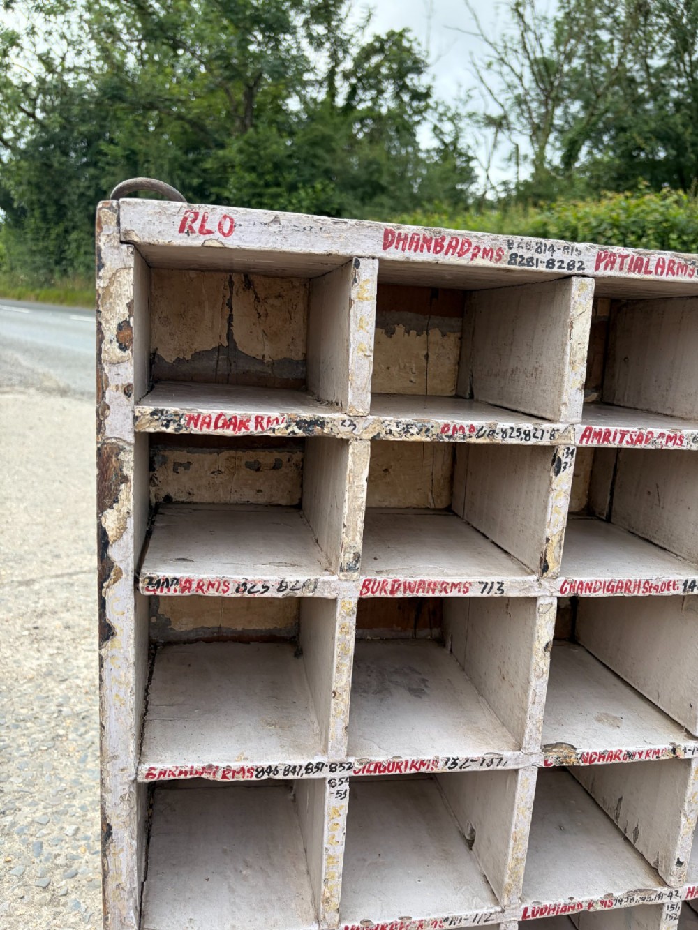 An early twentieth-century painted pine pigeon hole storage unit with a rectangular grid layout and red painted slot labels. View VIII