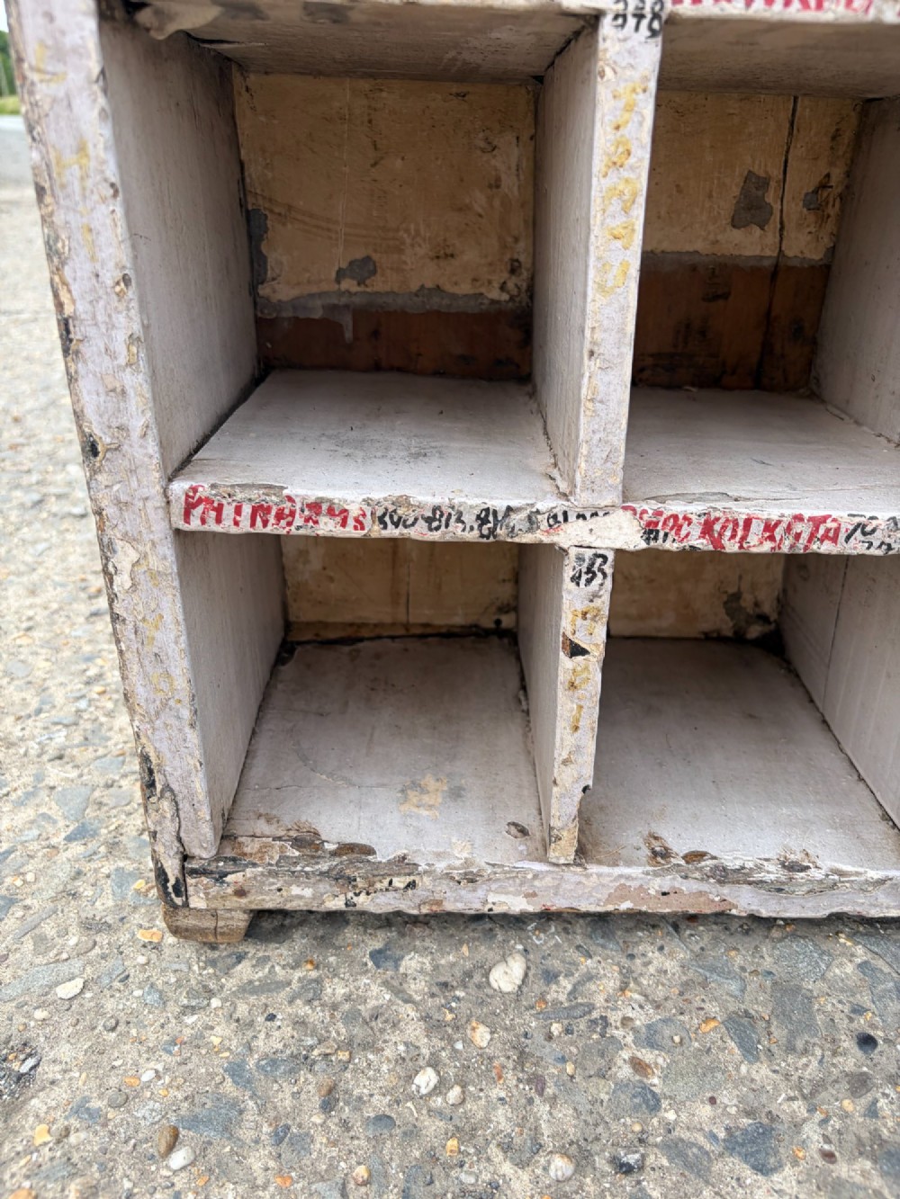 An early twentieth-century painted pine pigeon hole storage unit with a rectangular grid layout and red painted slot labels. View X