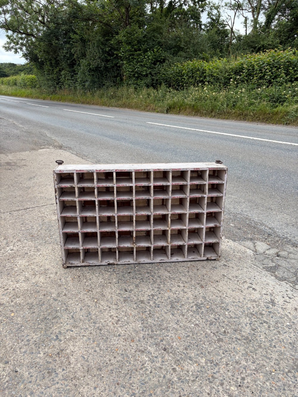 An early twentieth-century painted pine pigeon hole storage unit with a rectangular grid layout and red painted slot labels.