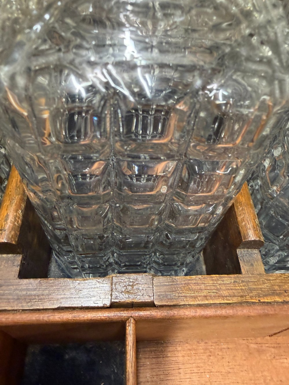 A late Victorian carved oak tantalus set featuring brass corner mounts, a front compartment with carved scrollwork, and three cut glass decanters backed by a mirror. View IX
