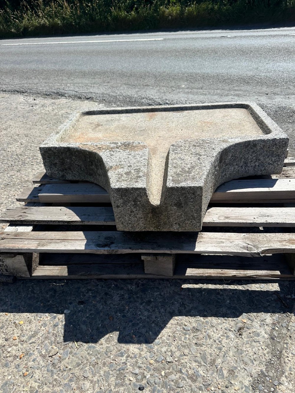 A hand-carved grey granite press stone featuring a recessed rectangular basin with an extended drainage spout. View II