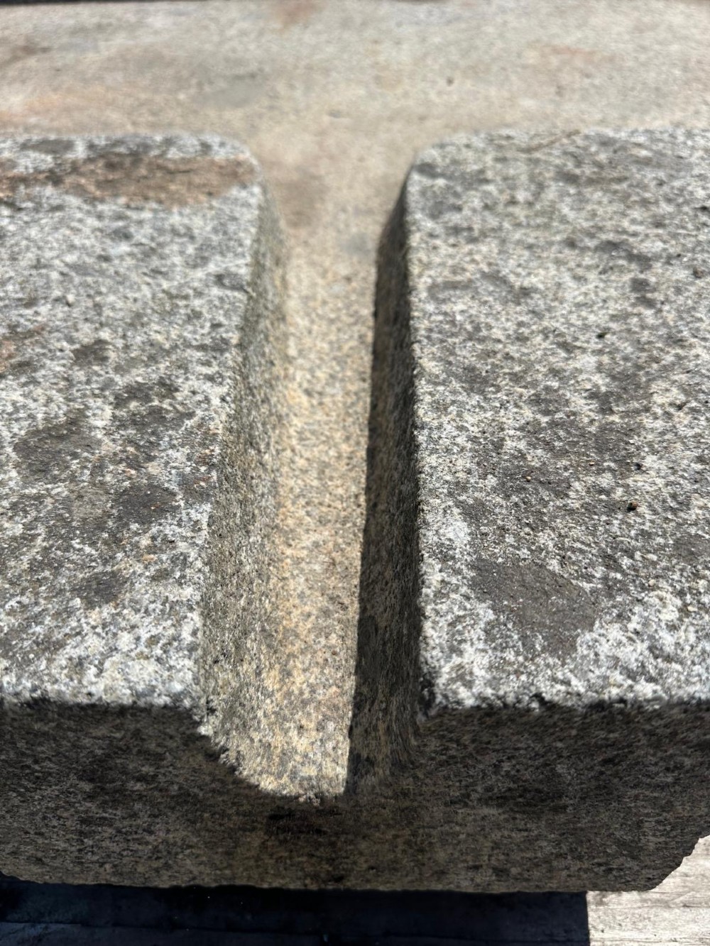 A hand-carved grey granite press stone featuring a recessed rectangular basin with an extended drainage spout. View III