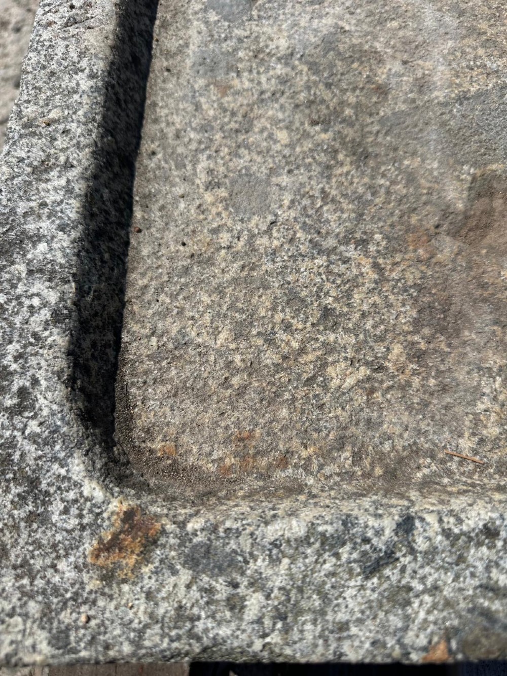 A hand-carved grey granite press stone featuring a recessed rectangular basin with an extended drainage spout. View V