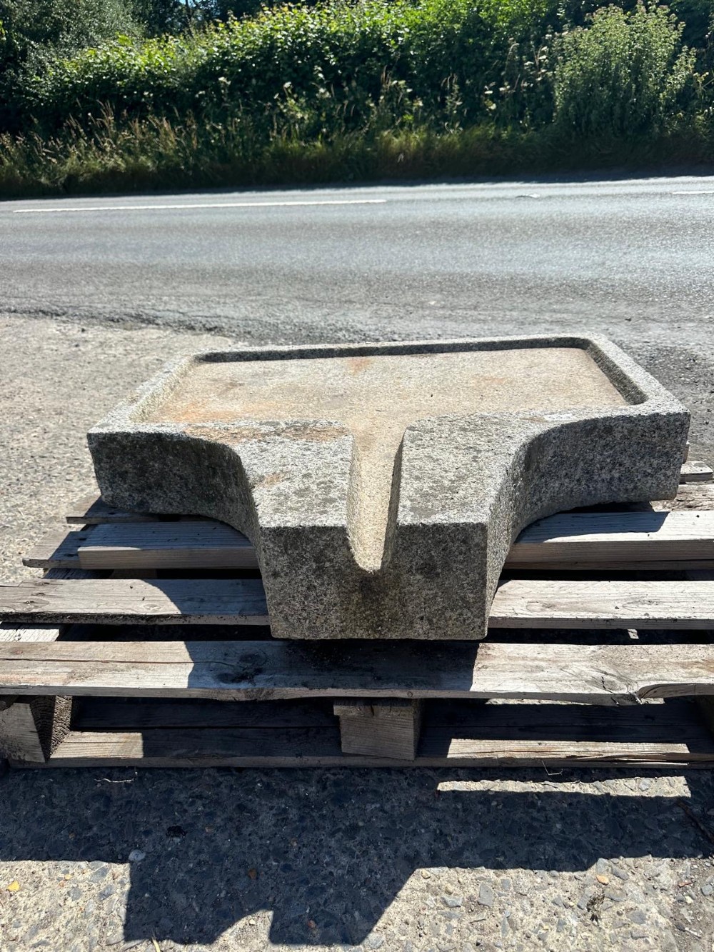 A hand-carved grey granite press stone featuring a recessed rectangular basin with an extended drainage spout. View VI