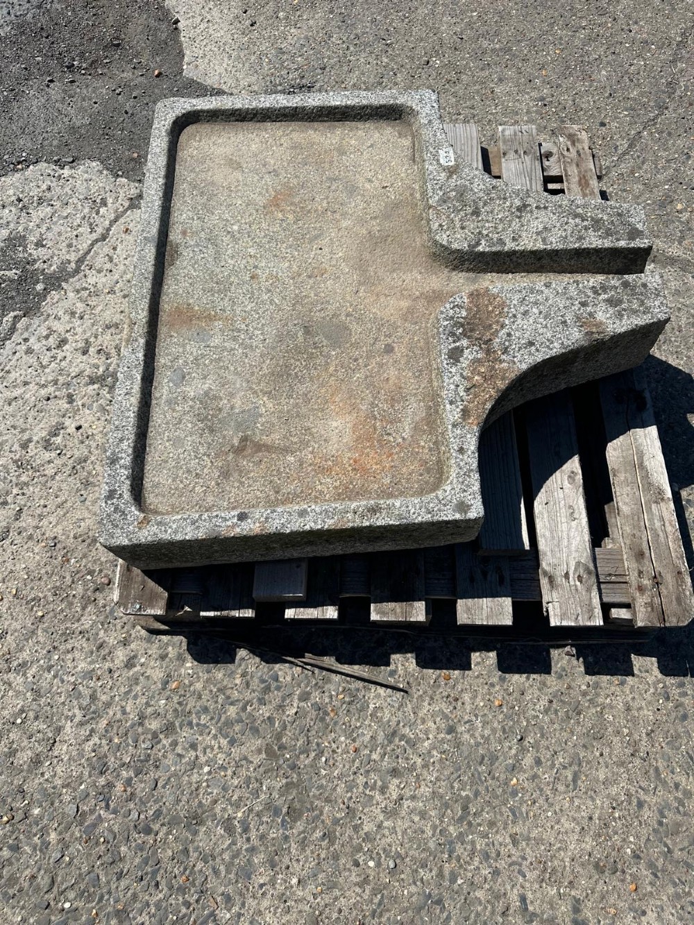 A hand-carved grey granite press stone featuring a recessed rectangular basin with an extended drainage spout. View VII