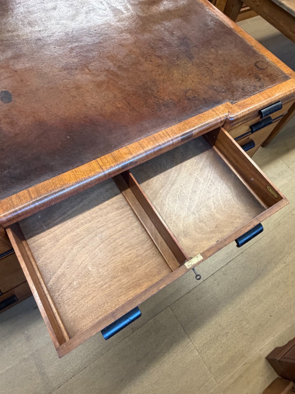 A large Art Deco walnut partner desk featuring a brown leather inset top and black horizontal drawer handles. View IX