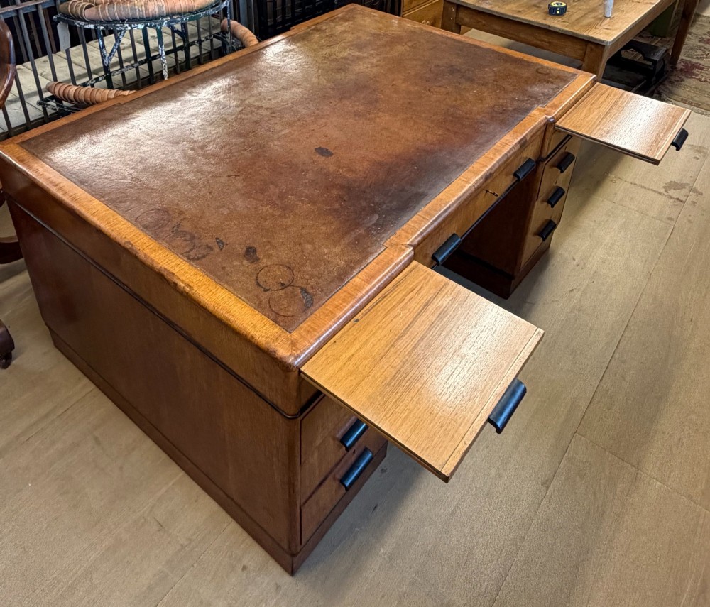 A large Art Deco walnut partner desk featuring a brown leather inset top and black horizontal drawer handles. View XI