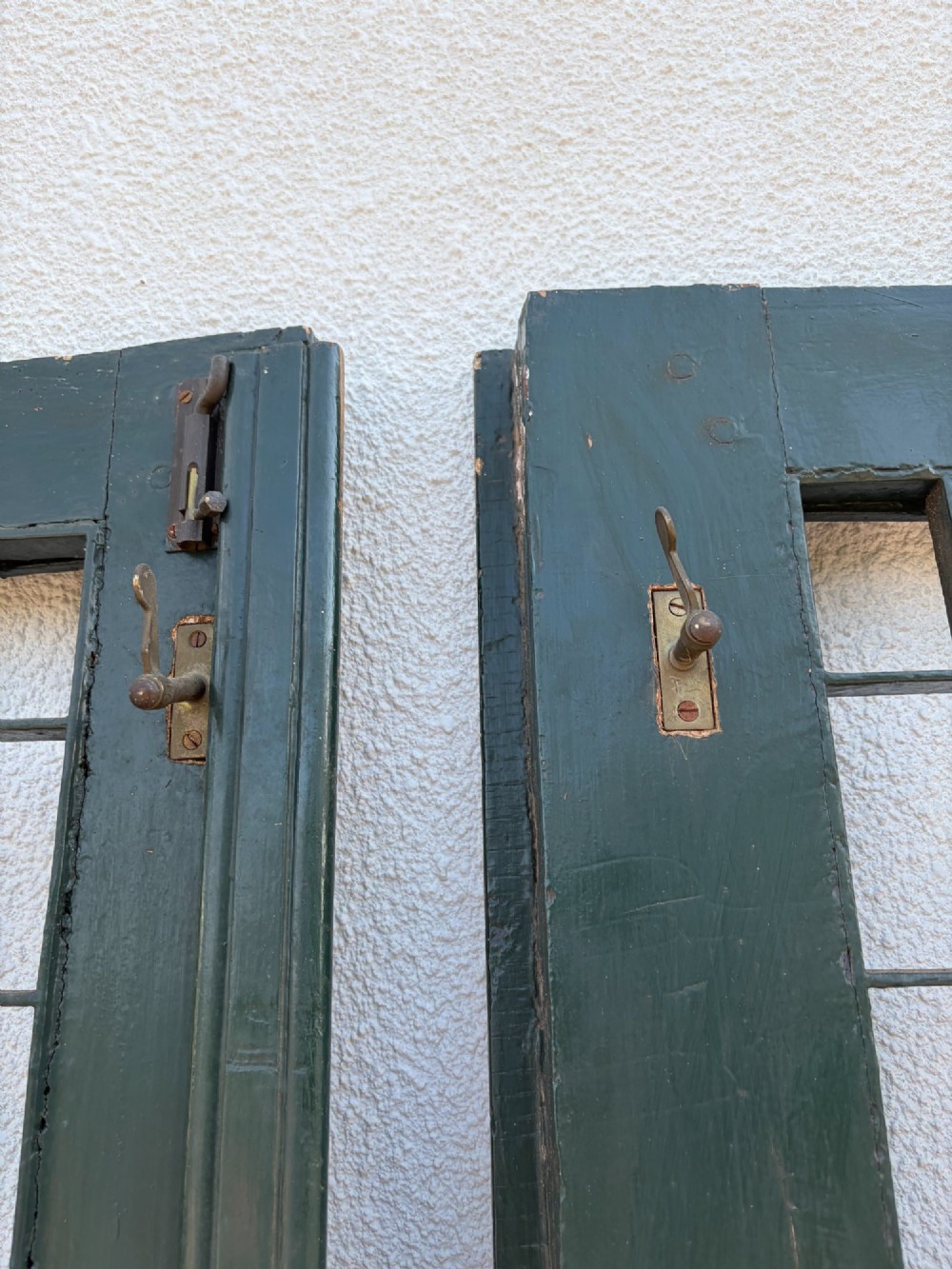 A pair of dark green painted pine double doors featuring arched tops, iron lattice grilles, and opening glazed window frames above solid lower timber panels. View V