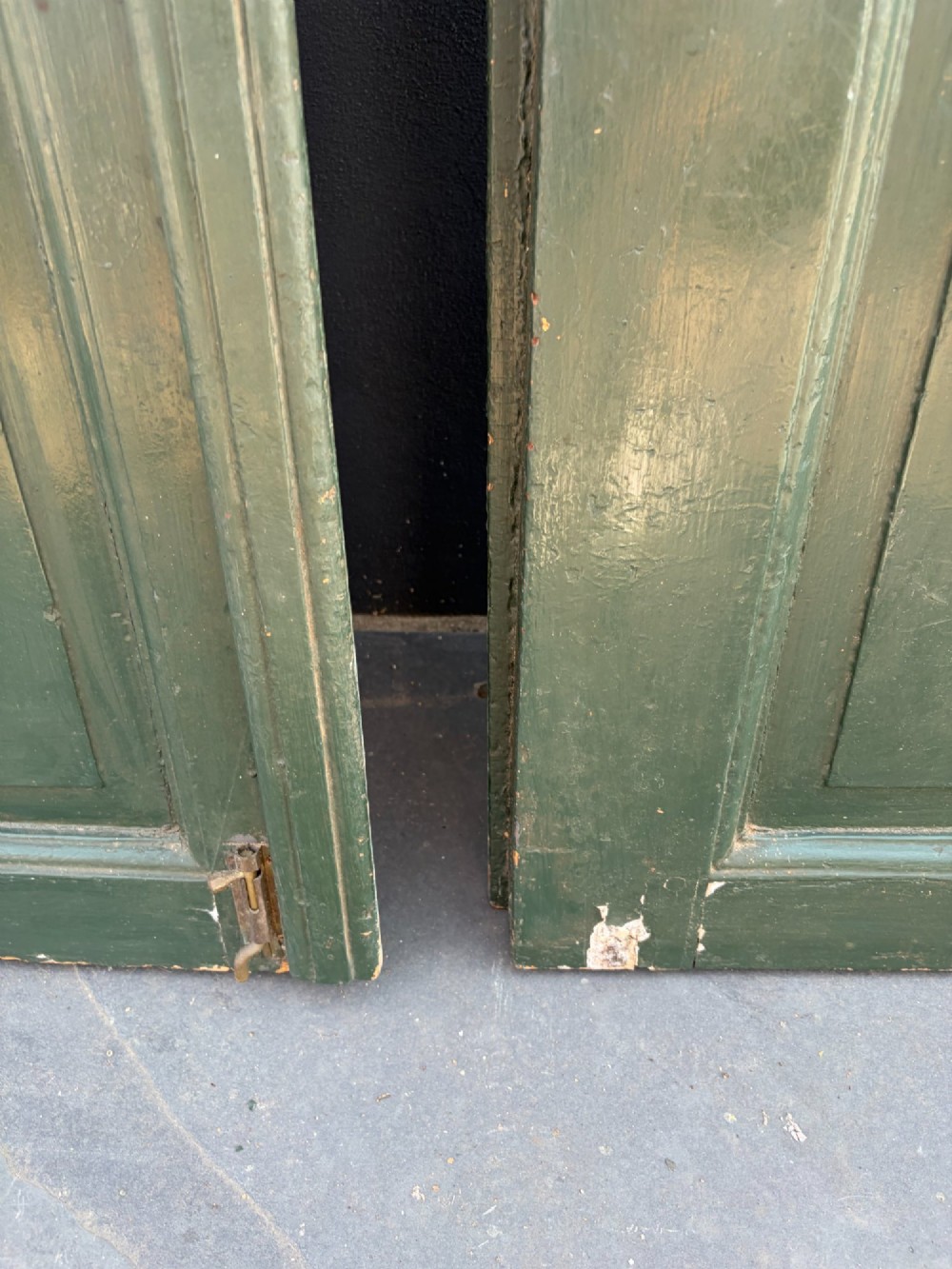 A pair of dark green painted pine double doors featuring arched tops, iron lattice grilles, and opening glazed window frames above solid lower timber panels. View VII