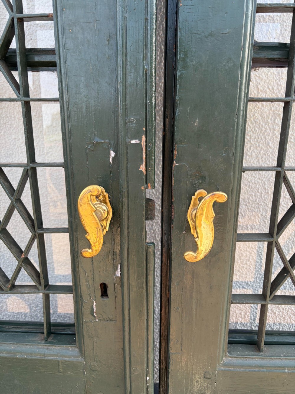 A pair of dark green painted pine double doors featuring arched tops, iron lattice grilles, and opening glazed window frames above solid lower timber panels. View IX