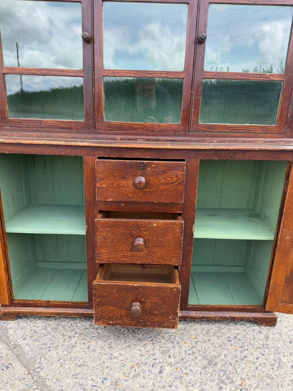 A dark stained Victorian pine dresser featuring a three-door glazed upper display cabinet over a base with three central drawers and two panelled cupboard doors. View V