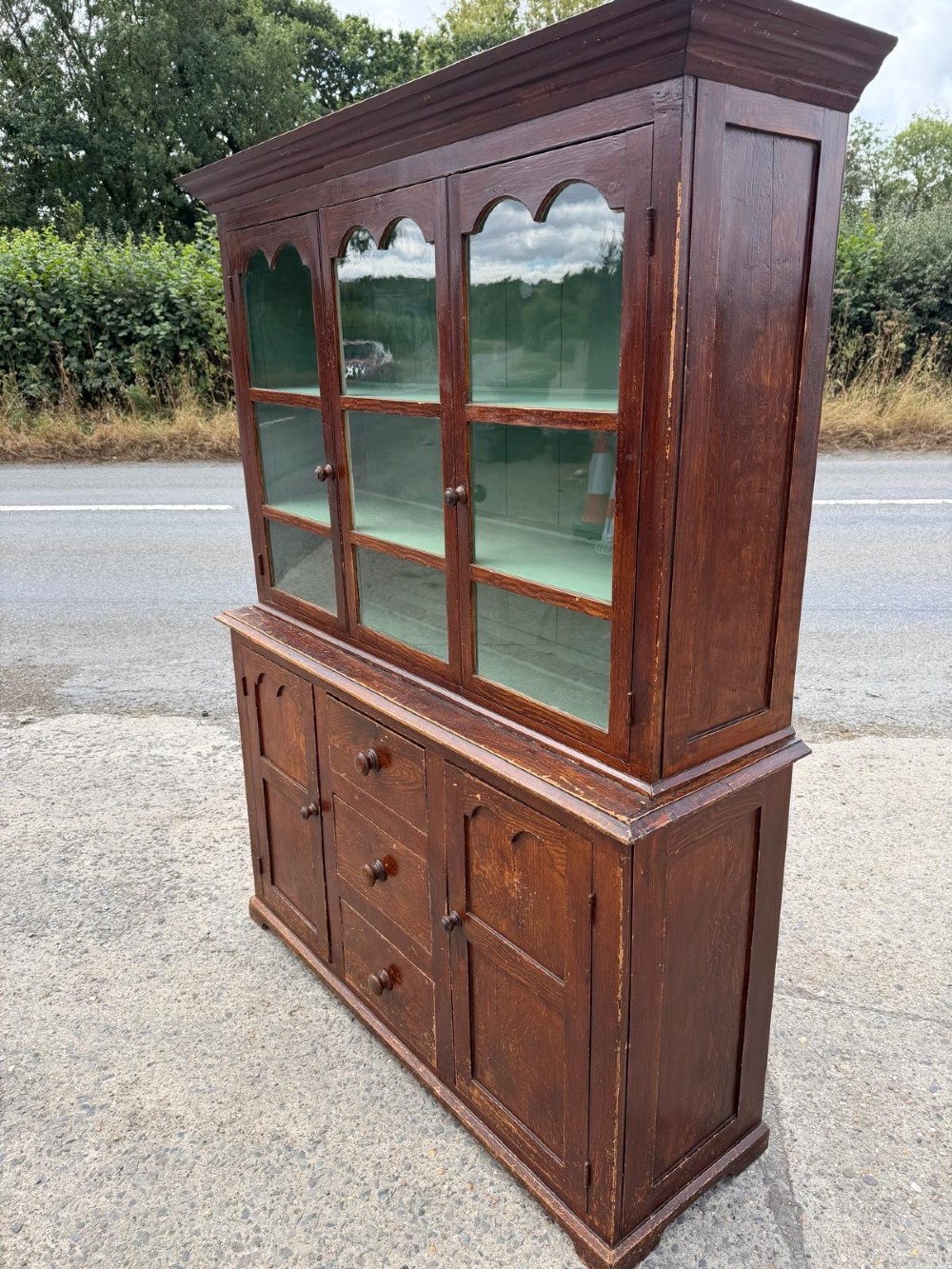 A dark stained Victorian pine dresser featuring a three-door glazed upper display cabinet over a base with three central drawers and two panelled cupboard doors. View VII
