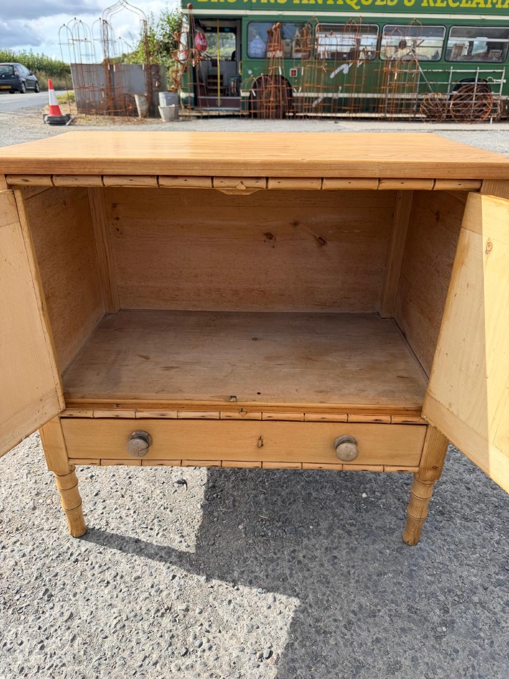 An early 19th-century light pine cupboard featuring double panelled doors, a single lower drawer, and carved faux bamboo frame trim and turned legs. View IV