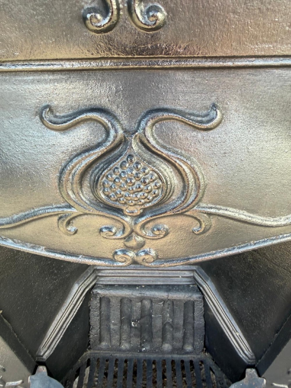 An antique Victorian cast iron combination fireplace featuring relief floral tendrils and seed pod motifs with an integrated grate and mantel shelf. View III