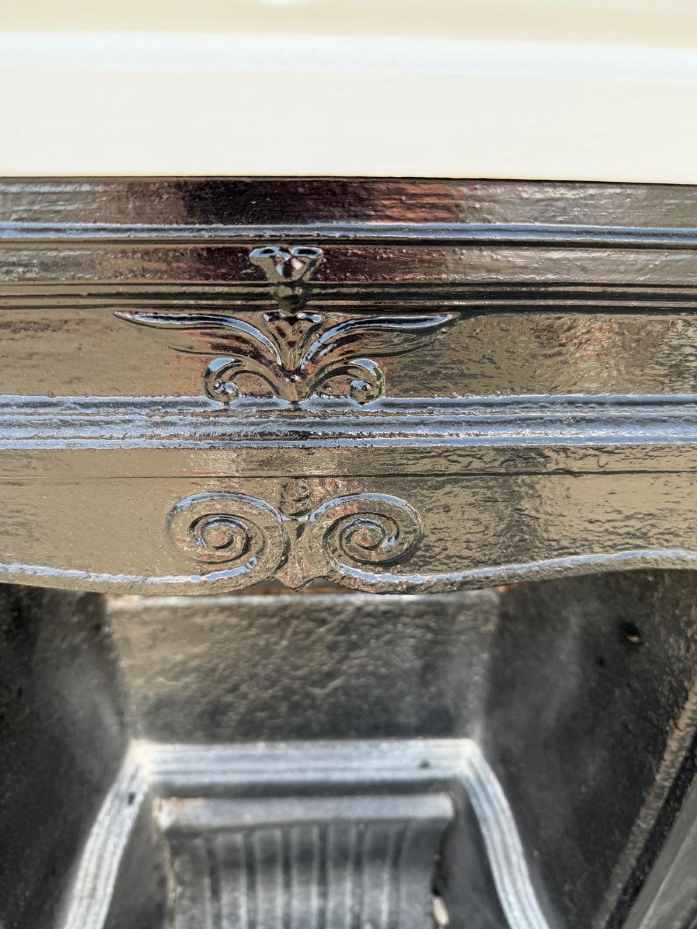 A Victorian combination fireplace featuring a white painted outer surround with raised floral relief patterns and a black cast iron inner grate insert. View II