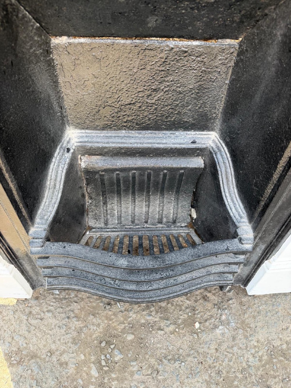 A Victorian combination fireplace featuring a white painted outer surround with raised floral relief patterns and a black cast iron inner grate insert. View VI