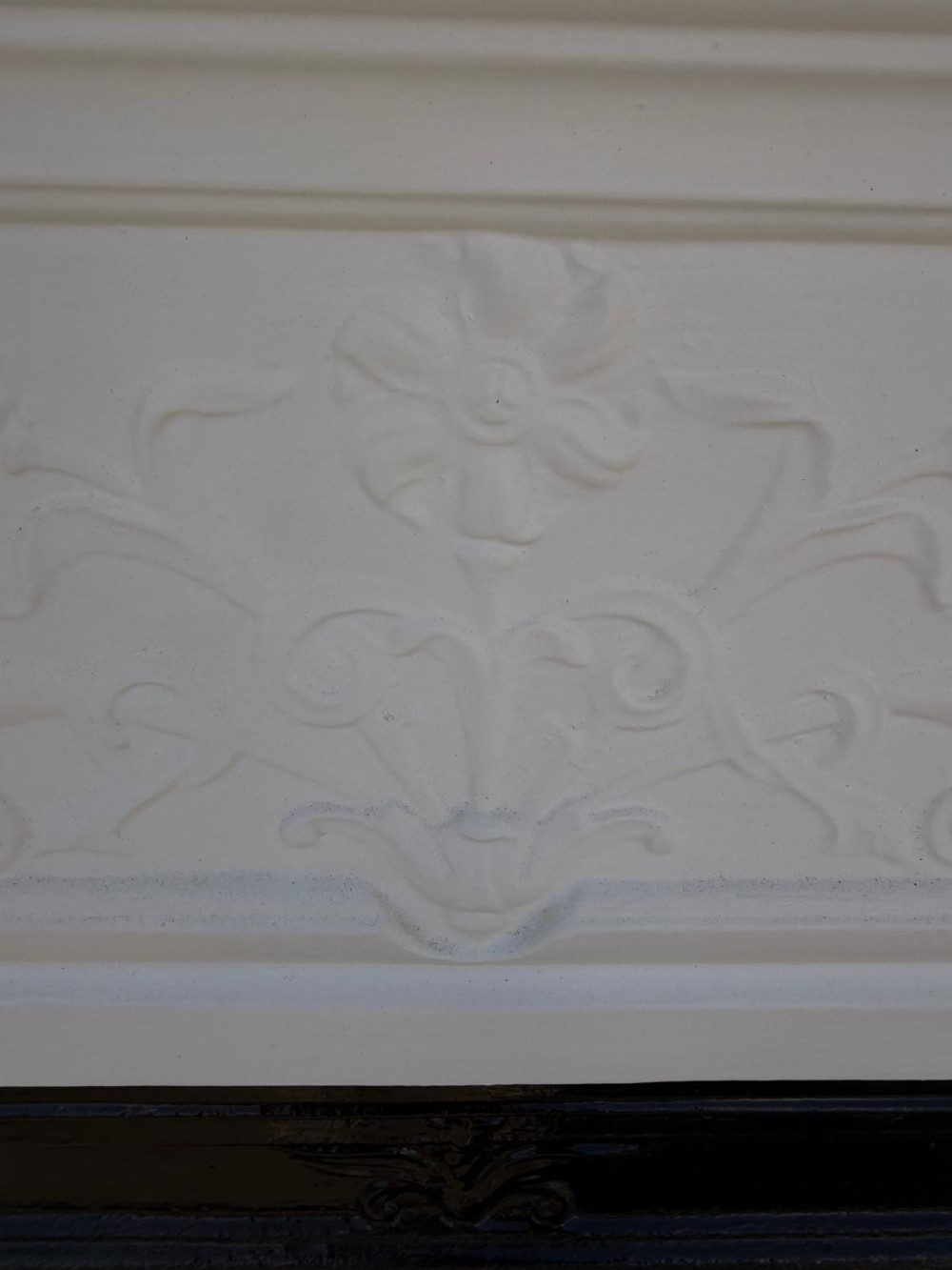 A Victorian combination fireplace featuring a white painted outer surround with raised floral relief patterns and a black cast iron inner grate insert. View VII