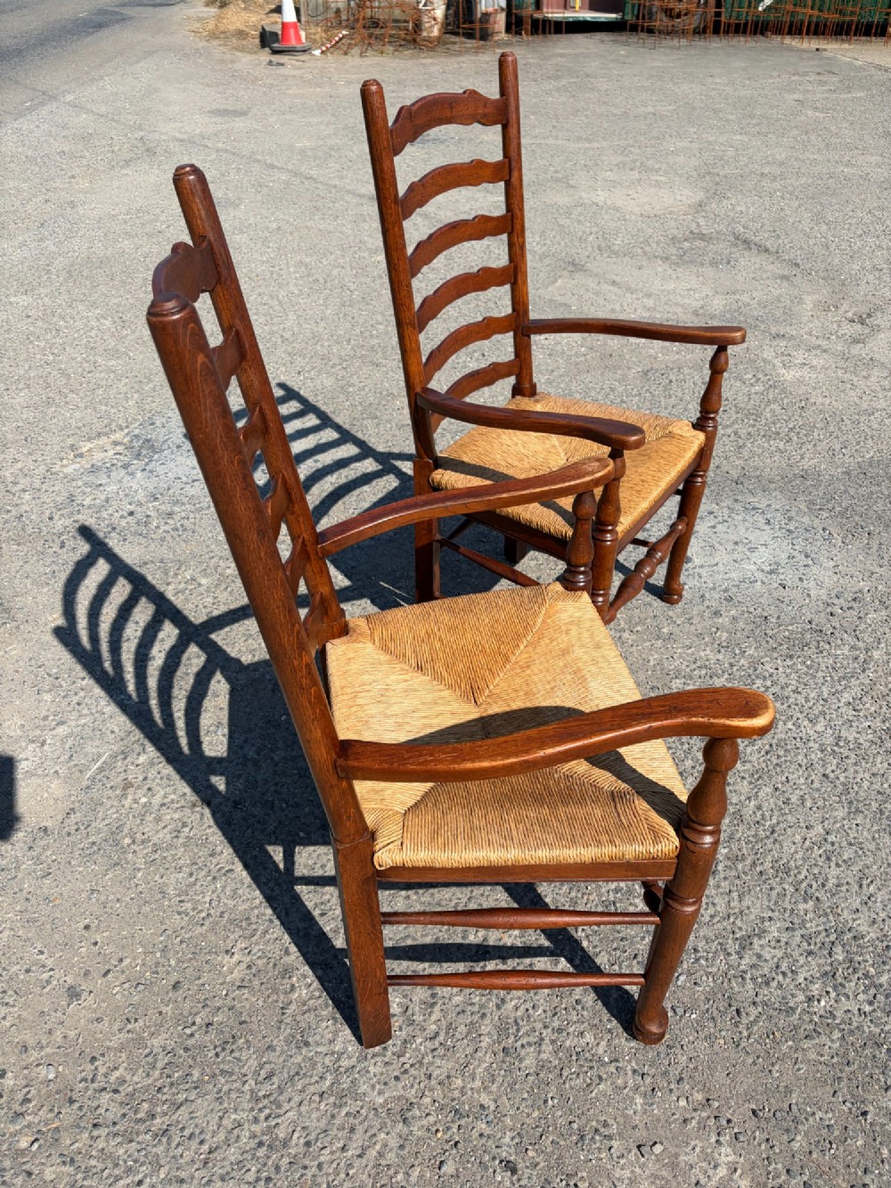 A pair of 19th-century Lancashire ladderback oak carver armchairs featuring curved back slats, turned stretchers, and hand-woven rush seats. View II