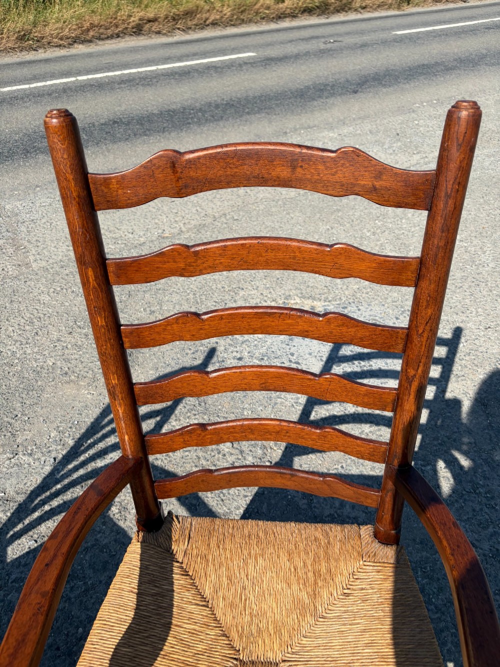 A pair of 19th-century Lancashire ladderback oak carver armchairs featuring curved back slats, turned stretchers, and hand-woven rush seats. View V