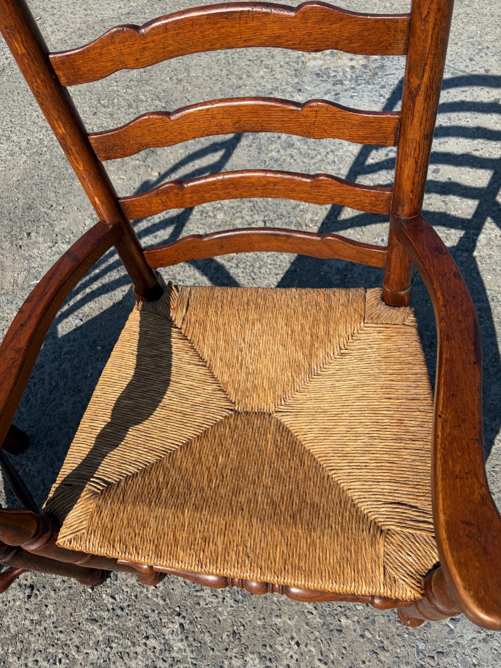 A pair of 19th-century Lancashire ladderback oak carver armchairs featuring curved back slats, turned stretchers, and hand-woven rush seats. View VI