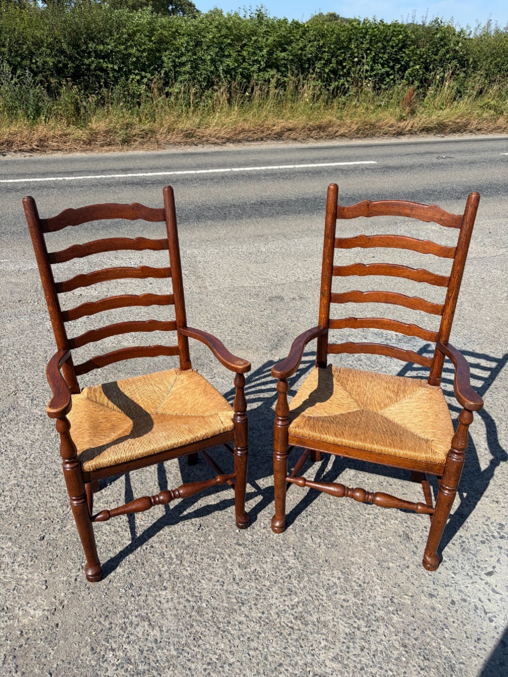 A pair of 19th-century Lancashire ladderback oak carver armchairs featuring curved back slats, turned stretchers, and hand-woven rush seats. View VII