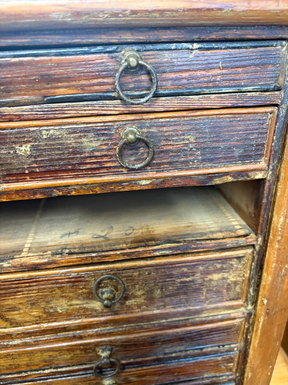 A 19th-century wooden bank of twenty-five individual drawers featuring metal ring pulls and a distressed dark finish. View II