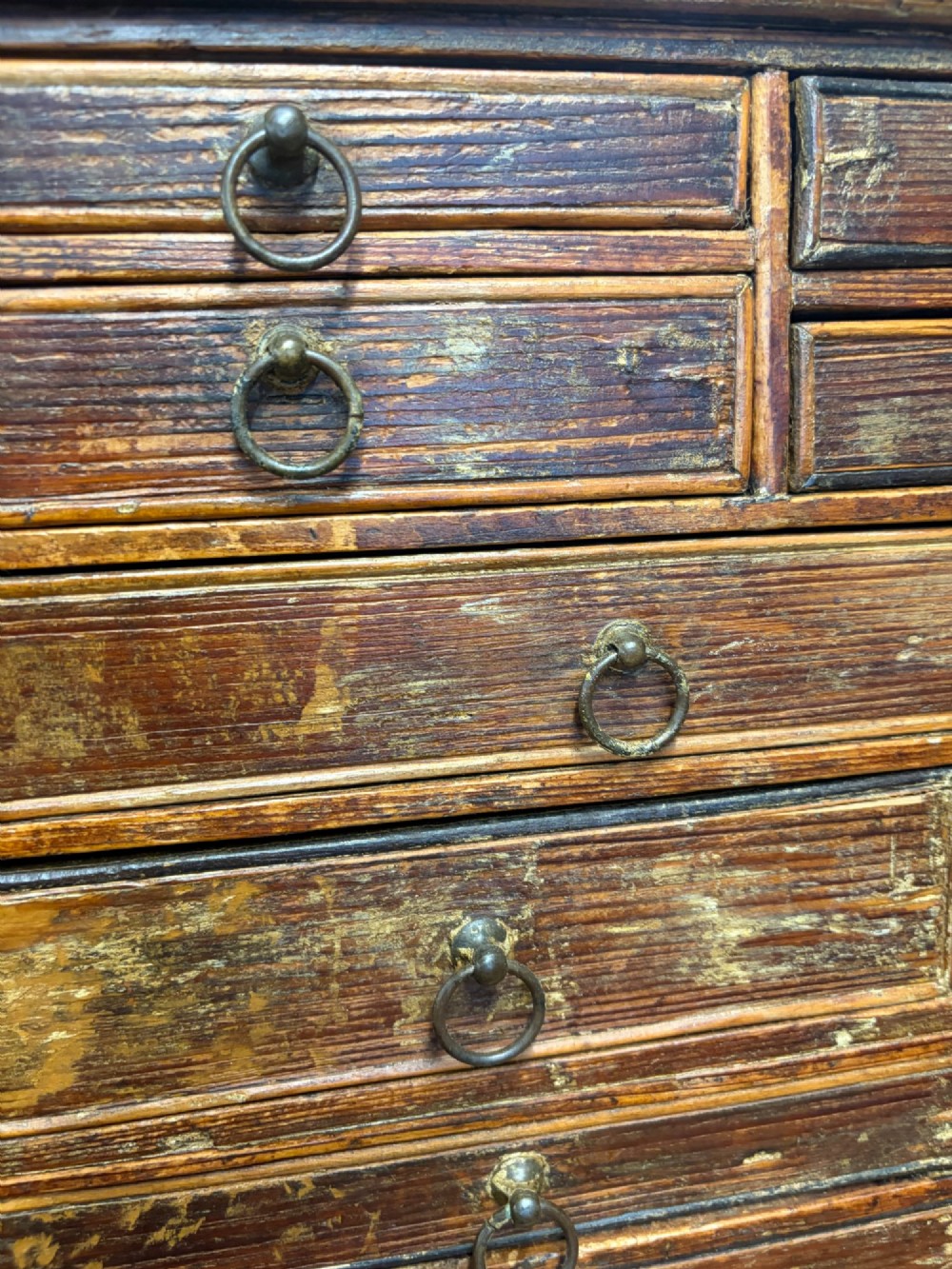 A 19th-century wooden bank of twenty-five individual drawers featuring metal ring pulls and a distressed dark finish. View IX