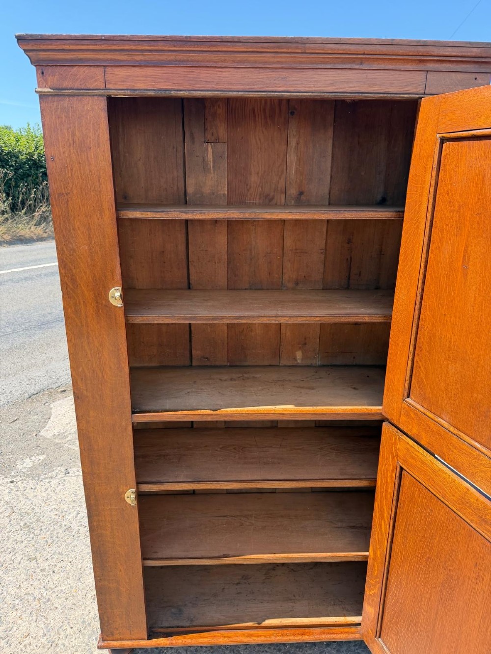 A tall Victorian oak two-door cupboard featuring recessed panel doors, turned wooden knobs, brass latches, and turned bun feet. View III